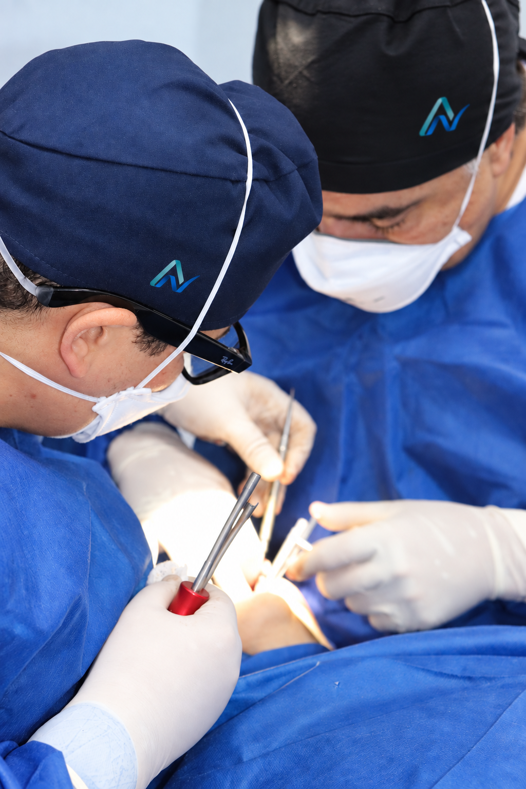 Médico de meia idade, sorrindo, com cabelos e barba grisalhos, usando um jaleco branco e de braços cruzados.